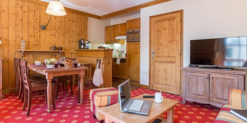 Arc 1950 le Village Arc 1950 Paradiski Frankrijk wintersport skivakantie luxe appartement Refuge du Montagnard gekleurde bank hocker salontafel laptop TV gedekte tafel houten stoelen hanglamp keuken hout