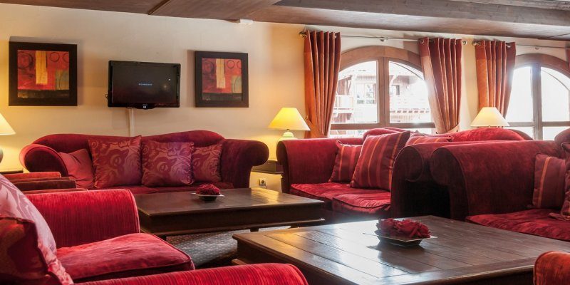 Arc 1950 le Village Arc 1950 Paradiski Frankrijk wintersport skivakantie luxe salon Le Manoir de Savoie rode banken rode kussens TV schilderij ronde ramen grote salontafels lampen houten balken