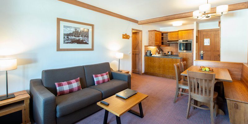 Arc 1950 le Village Arc 1950 Paradiski Frankrijk wintersport skivakantie luxe living grijze bank kussens salontafel laptop lamp eettafel hoekbank houten stoelen lamp keuken schilderij