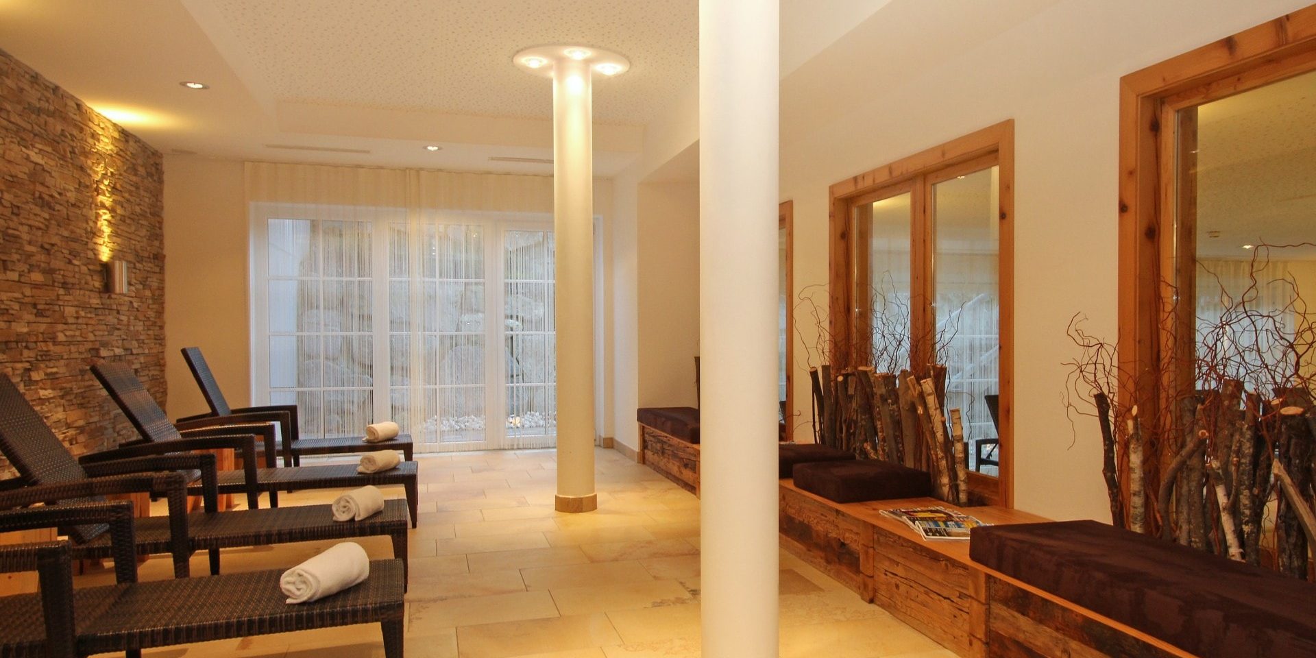 Avenida Mountain Resort Kaprun Zell am See-Kaprun Oostenrijk wintersport skivakantie luxe Spa ligbedden handdoeken stenen muur pilaren hout boomstammen ramen wandlamp