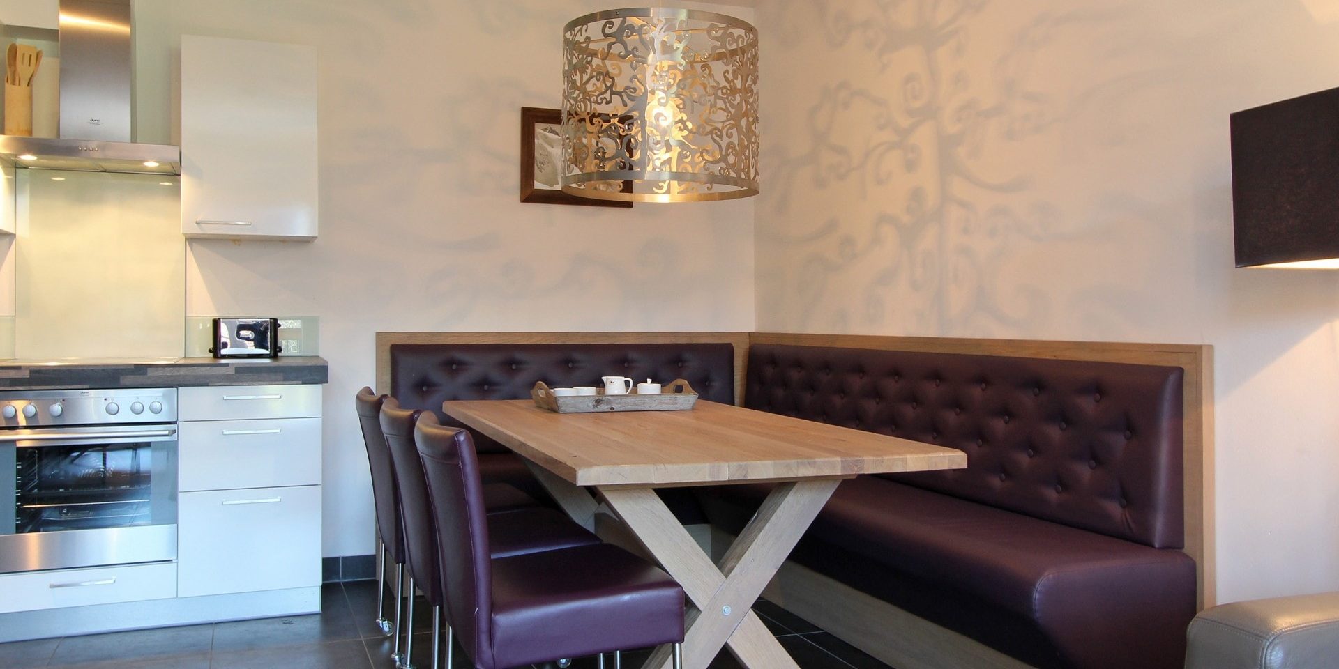 Avenida Mountain Resort Kaprun Zell am See-Kaprun Oostenrijk wintersport skivakantie luxe B13 eettafel paarse stoelen paarse hoekbank hanglamp keuken afzuigkap schilderij