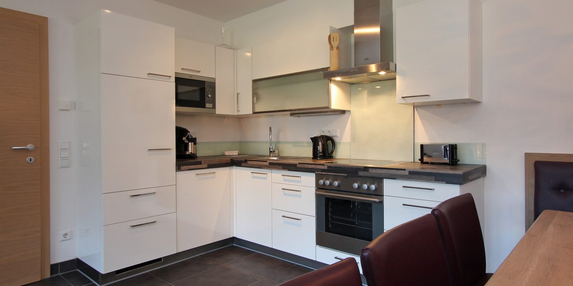 Avenida Mountain Resort Kaprun Zell am See-Kaprun Oostenrijk wintersport skivakantie luxe B13 witte keuken afzuigkap kookplaat eettafel bruine leren stoelen