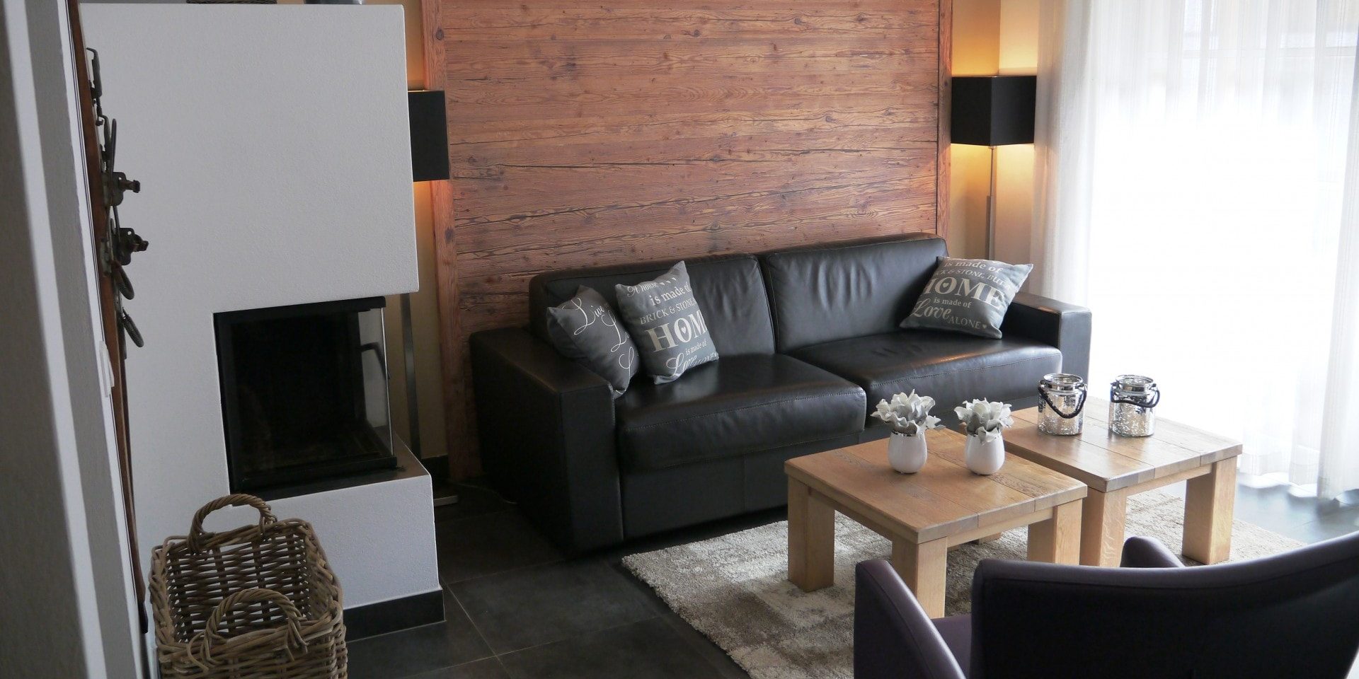 Avenida Mountain Resort Kaprun Zell am See-Kaprun Oostenrijk wintersport skivakantie luxe D17 living zwarte bank open haard paarse fauteuil salontafels kaarsen plantjes wandlampen mand raam