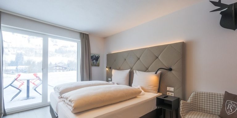 Hotel Avenida Panorama Suites Kaprun Zell am See-Kaprun Oostenrijk wintersport skivakantie luxe Studio slaapkamer aparte bedden hoofdbord hert bankje kussen terras tafel stoelen