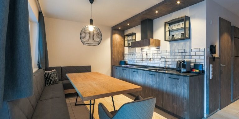 Hotel Avenida Panorama Suites Kaprun Zell am See-Kaprun Oostenrijk wintersport skivakantie luxe Suites 113 114 eettafel hoekbank kussens stoel hanglamp raam keuken spotjes