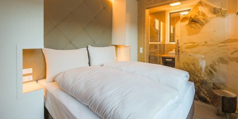 Hotel Avenida Panorama Suites Kaprun Zell am See-Kaprun Oostenrijk wintersport skivakantie luxe Suites 2-persoonsbed hoofdbord kruk muurschildering badkamer wastafel spiegel