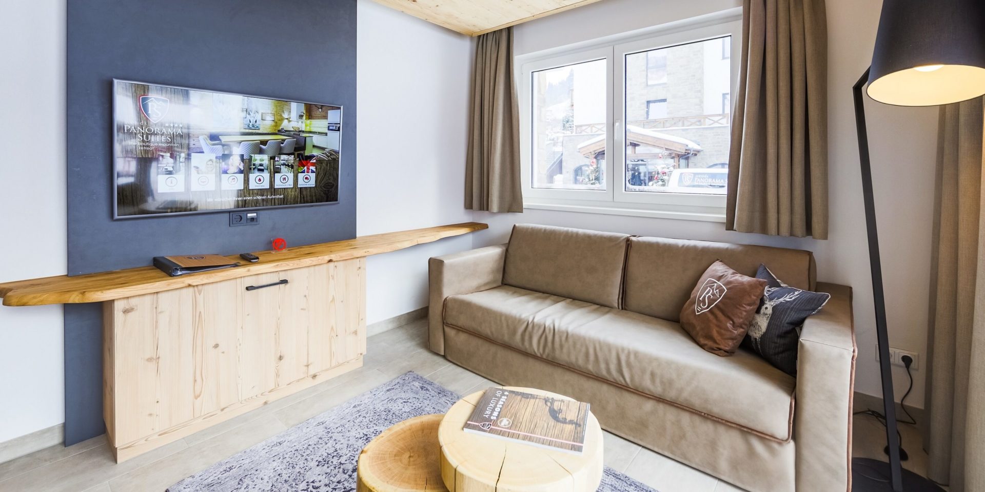 Hotel Avenida Panorama Suites Kaprun Zell am See-Kaprun Oostenrijk wintersport skivakantie luxe Suites Sauna 323 living bank kussens salontafel TV kast raam lamp grijze muur gordijnen