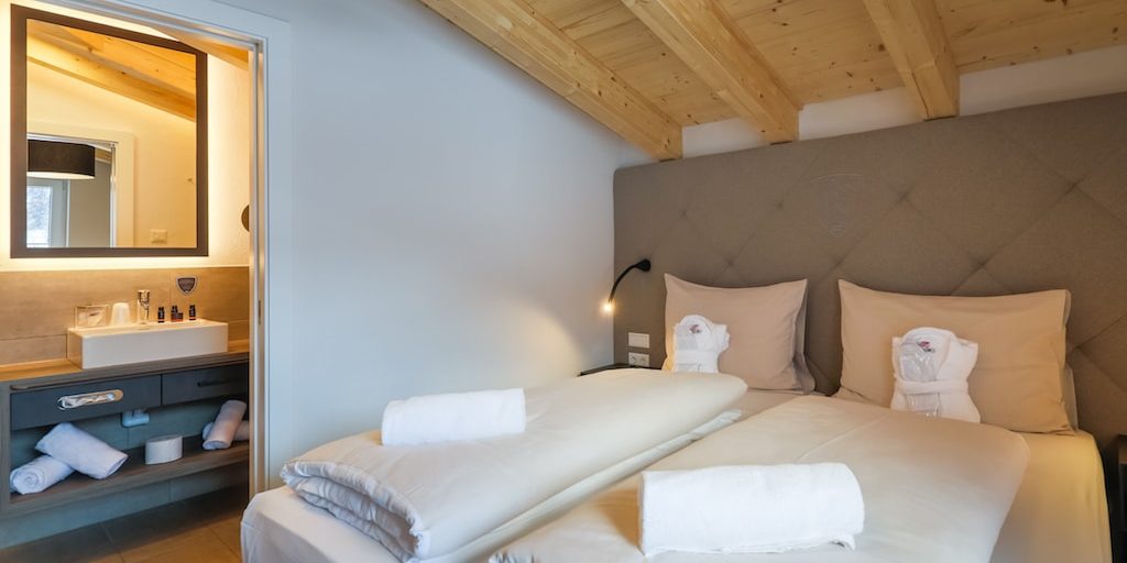 Penthouses Avenida Panorama Suites Kaprun Zell am See-Kaprun Oostenrijk wintersport skivakantie luxe Penthouse 4 slaapkamer 2-persoonsbed hoofdbord nachtlampje badkamer wastafel spiegel handdoeken houten balken