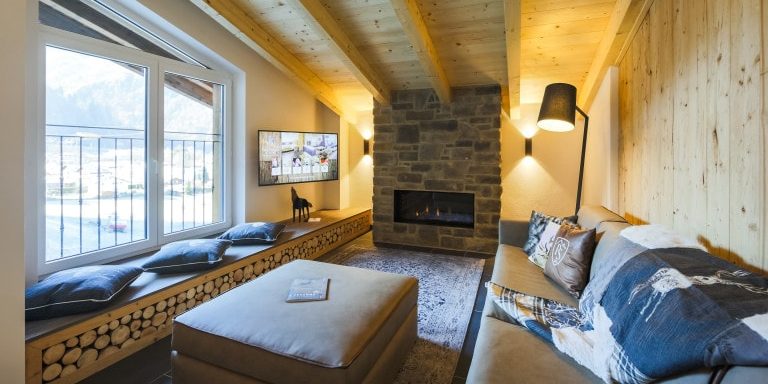 Penthouses Avenida Panorama Suites Kaprun Zell am See-Kaprun Oostenrijk wintersport skivakantie luxe Penthouse MIVA leren bank kussens kleed hocker TV open haard raam houten wand houten balken