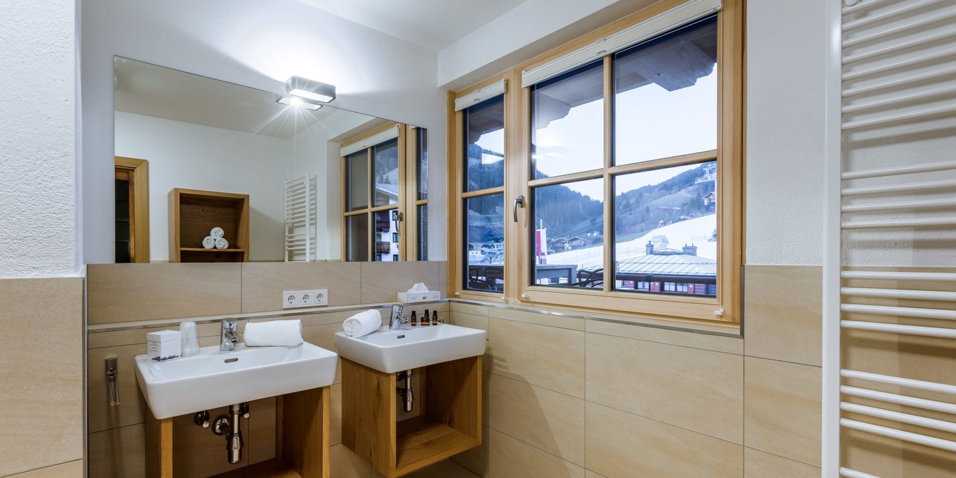Bolodge 1 Saalbach Skicircus Saalbach Hinterglemm Oostenrijk wintersport skivakantie luxe badkamer dubbele wasbak grote spiegel handdoekenrek raam sneeuw
