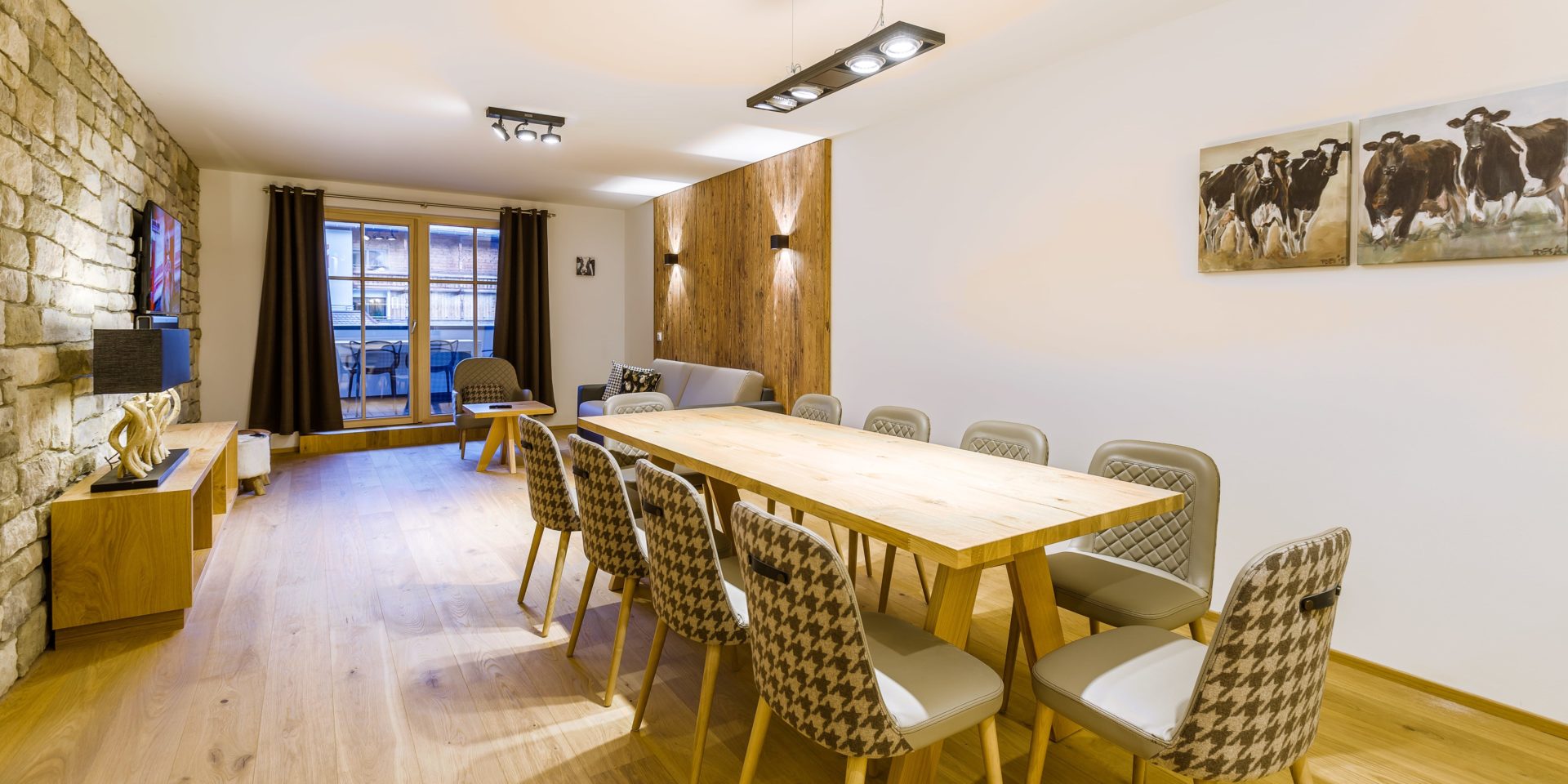 Bolodge 1 Saalbach Skicircus Saalbach Hinterglemm Oostenrijk wintersport skivakantie luxe eettafel stoelen schilderijen koeien TV kast bank fauteuil wandlampen balkon tafel stoelen