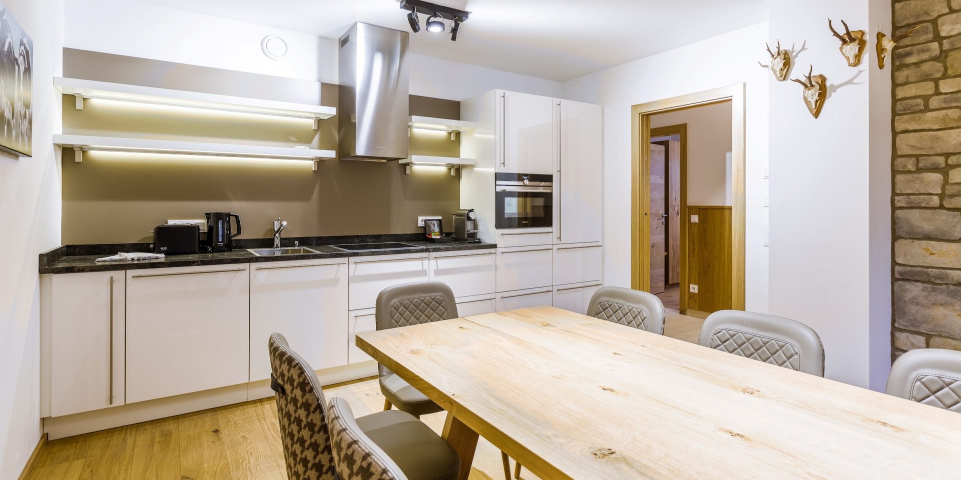 Bolodge 1 Saalbach Skicircus Saalbach Hinterglemm Oostenrijk wintersport skivakantie luxe eettafel stoelen gewei keuken kookplaat afzuigkap stenen muur schilderij koe