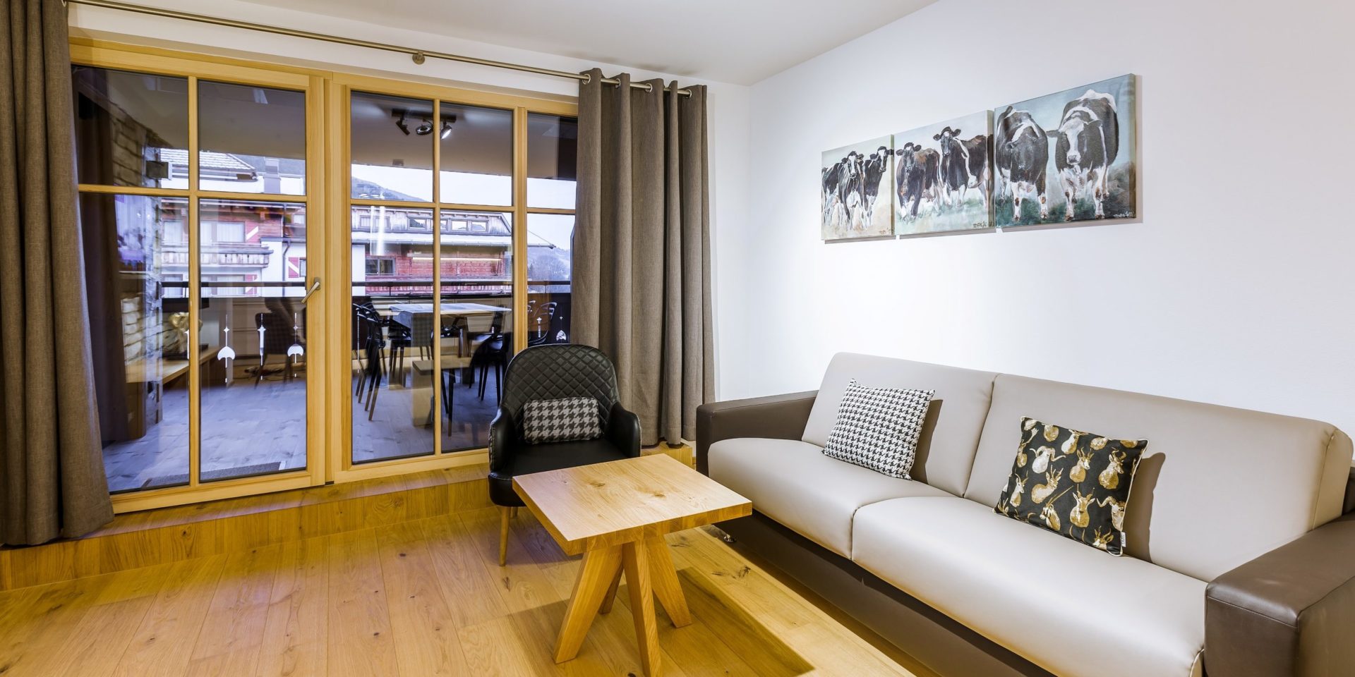 Bolodge 1 Saalbach Skicircus Saalbach Hinterglemm Oostenrijk wintersport skivakantie luxe bank fauteuil schilderijen koeien salontafel grote ramen balkon tafel stoelen