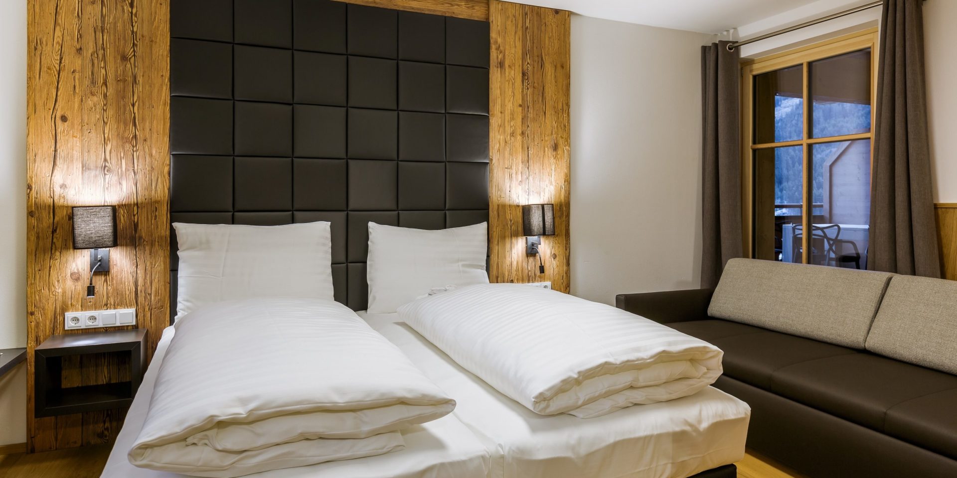 Bolodge 1 Saalbach Skicircus Saalbach Hinterglemm Oostenrijk wintersport skivakantie luxe slaapkamer 2-persoonsbed hoofdbord leren bank raam hout