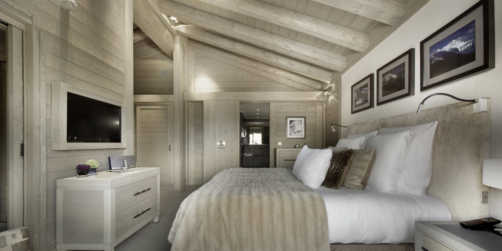 Le K2 Palace Suite-Chalet Abruzzes Courchevel Les 3 Vallees Frankrijk wintersport skivakantie luxe slaapkamer 2-persoonsbed kussens sprei TV schilderijen houten balken houten plafond