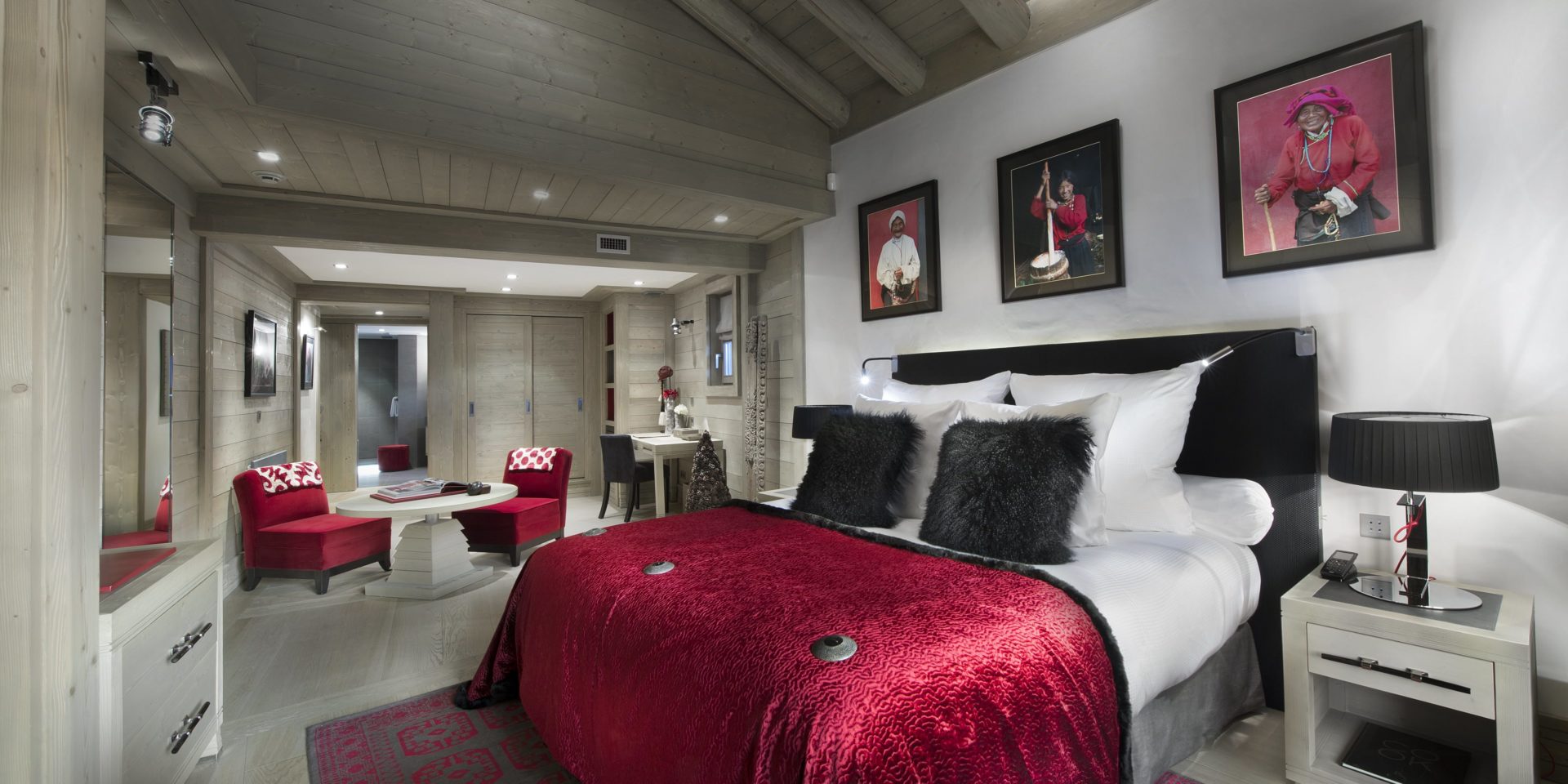 Le K2 Palace Suite-Chalet Baltoro Courchevel Les 3 Vallees Frankrijk wintersport skivakantie luxe slaapkamer 2-persoonsbed kussens schilderijen rode fauteuils salontafel bureau stoel vloerkleed spiegel houten balken