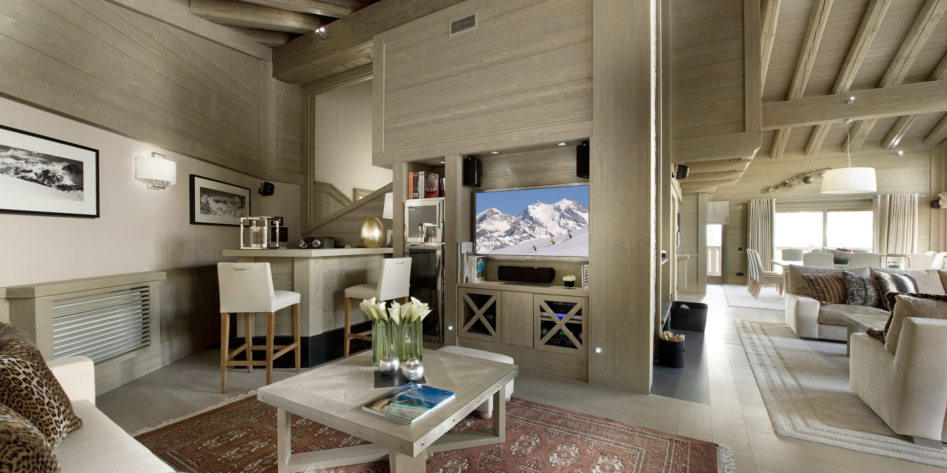 Le K2 Palace Suite-Chalet Karakoram Courchevel Les 3 Vallees Frankrijk wintersport skivakantie luxe living banken kussens salontafel schilderijen TV bar barkrukken hout houten balken