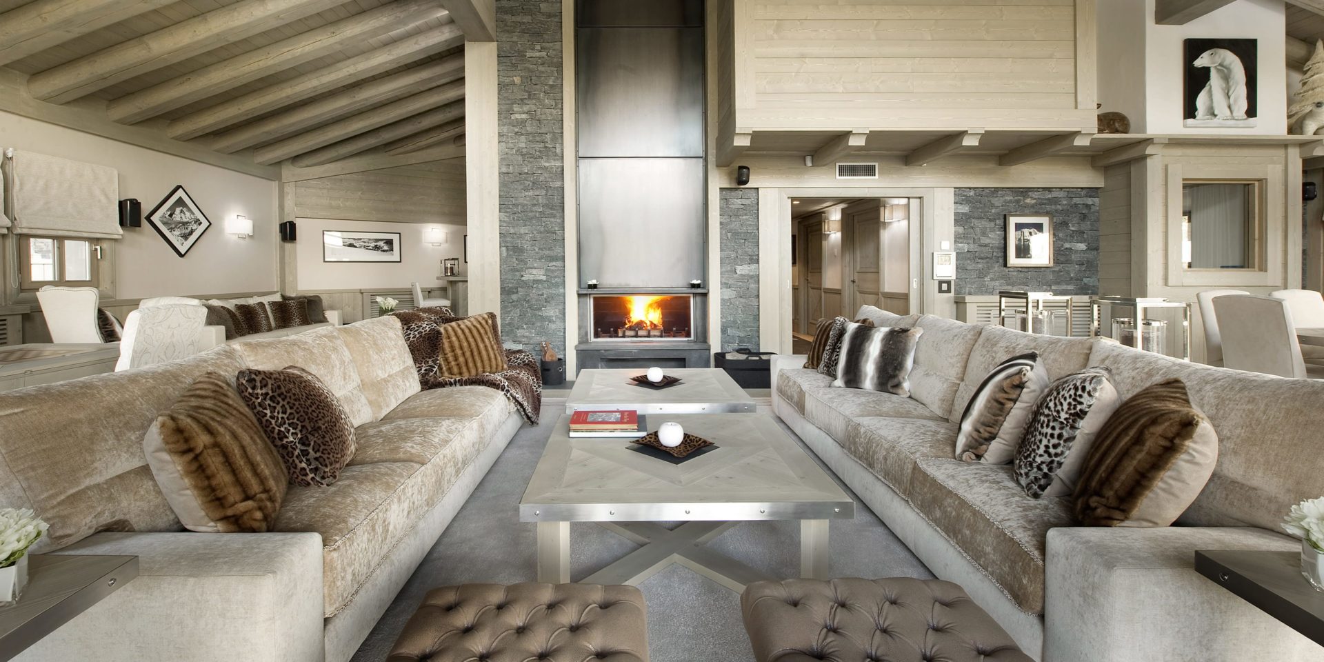 Le K2 Palace Suite-Chalet Karakoram Courchevel Les 3 Vallees Frankrijk wintersport skivakantie luxe living open haard grote witte banken kussens salontafels hockers schilderij ijsbeer hout houten balken