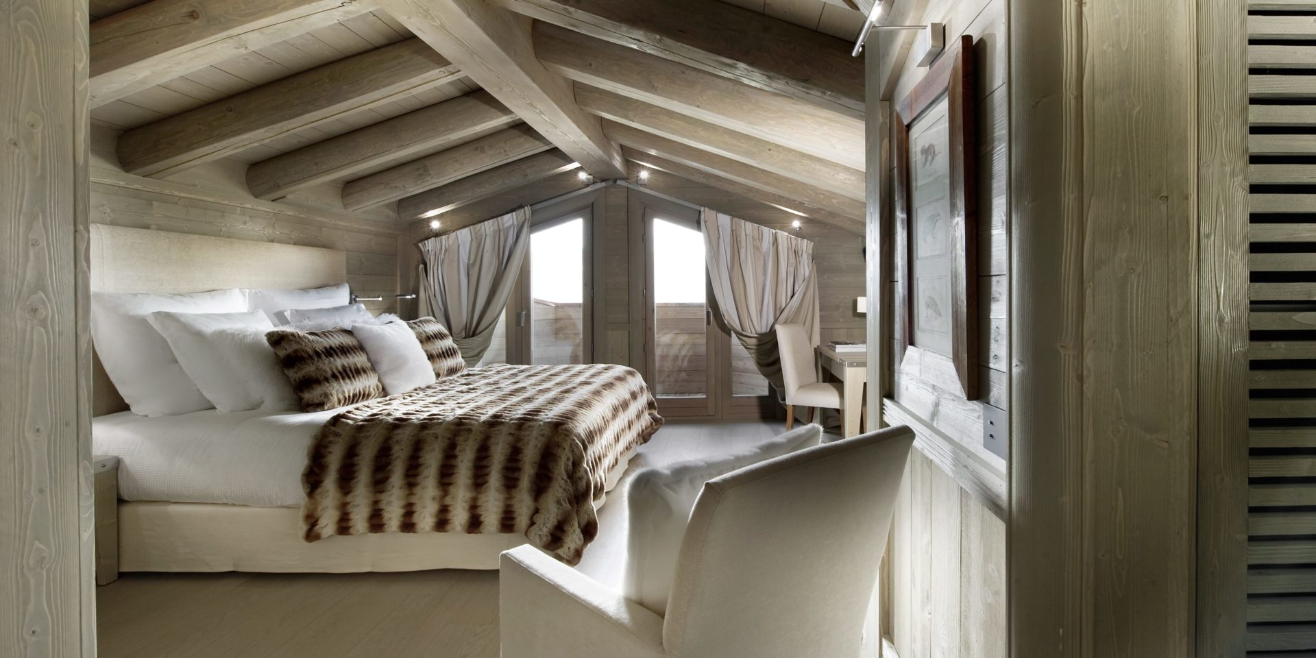 Le K2 Palace Suite-Chalet Karakoram Courchevel Les 3 Vallees Frankrijk wintersport skivakantie luxe slaapkamer 2-persoonsbed hoofdbord kussens fauteuil schilderij raam balkon houten balken