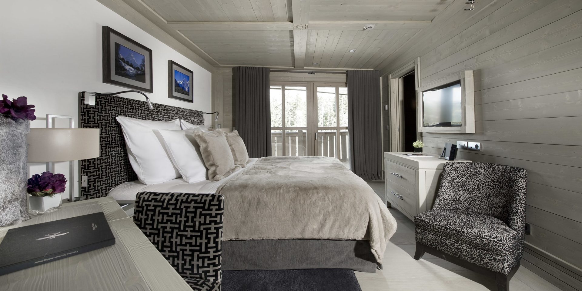 Le K2 Palace Suite-Chalet Muztagh Courchevel Les 3 Vallees Frankrijk wintersport skivakantie luxe slaapkamer 2-persoonsbed fauteuil TV kastje schilderijen bureau stoel raam balkon houten wanden houten plafond