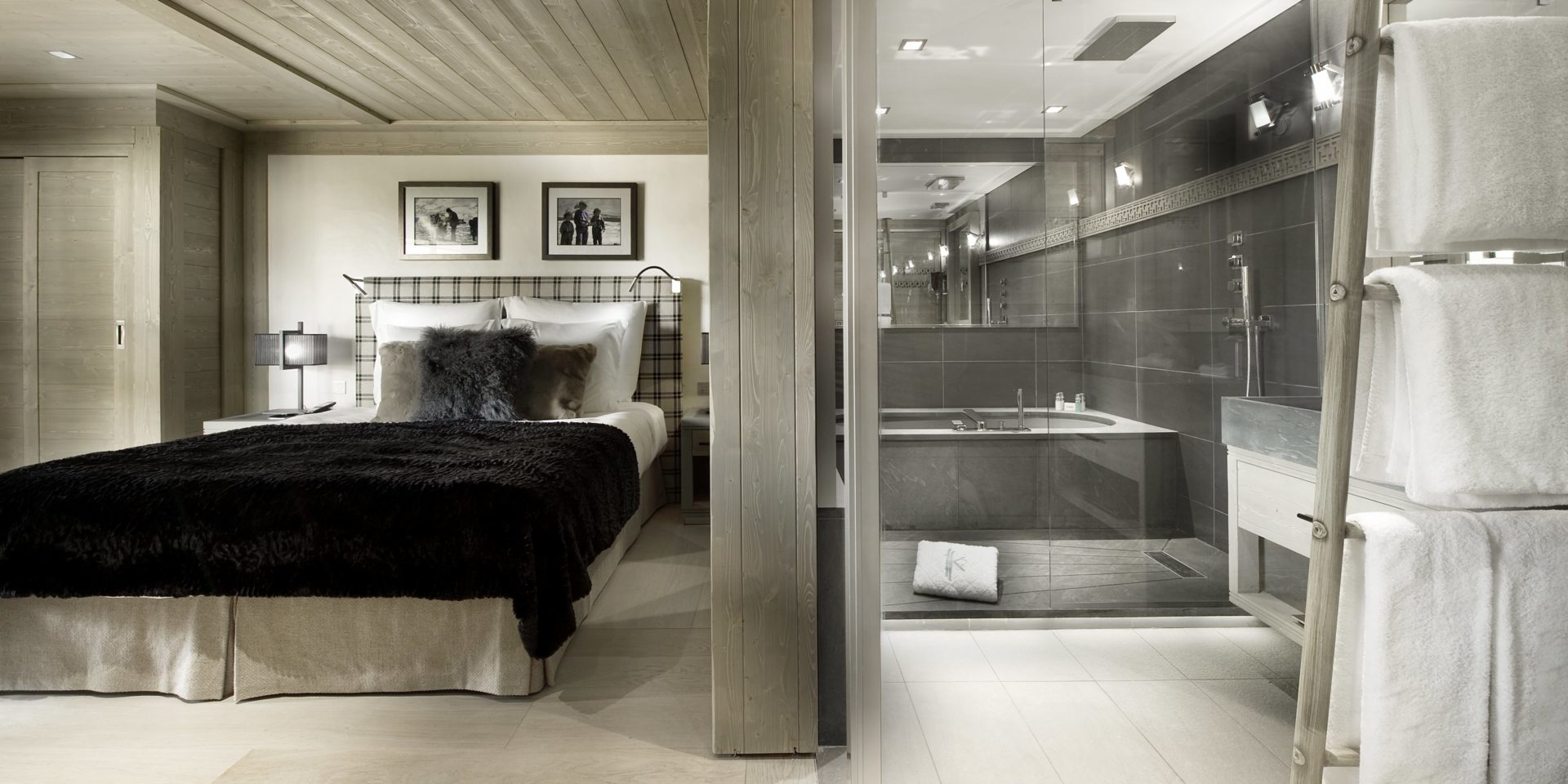 Le K2 Palace Suite-Chalet Muztagh Courchevel Les 3 Vallees Frankrijk wintersport skivakantie luxe slaapkamer 2-persoonsbed kussens zwarte sprei schilderijen badkamer bad grote spiegel wastafel handdoeken houten plafond