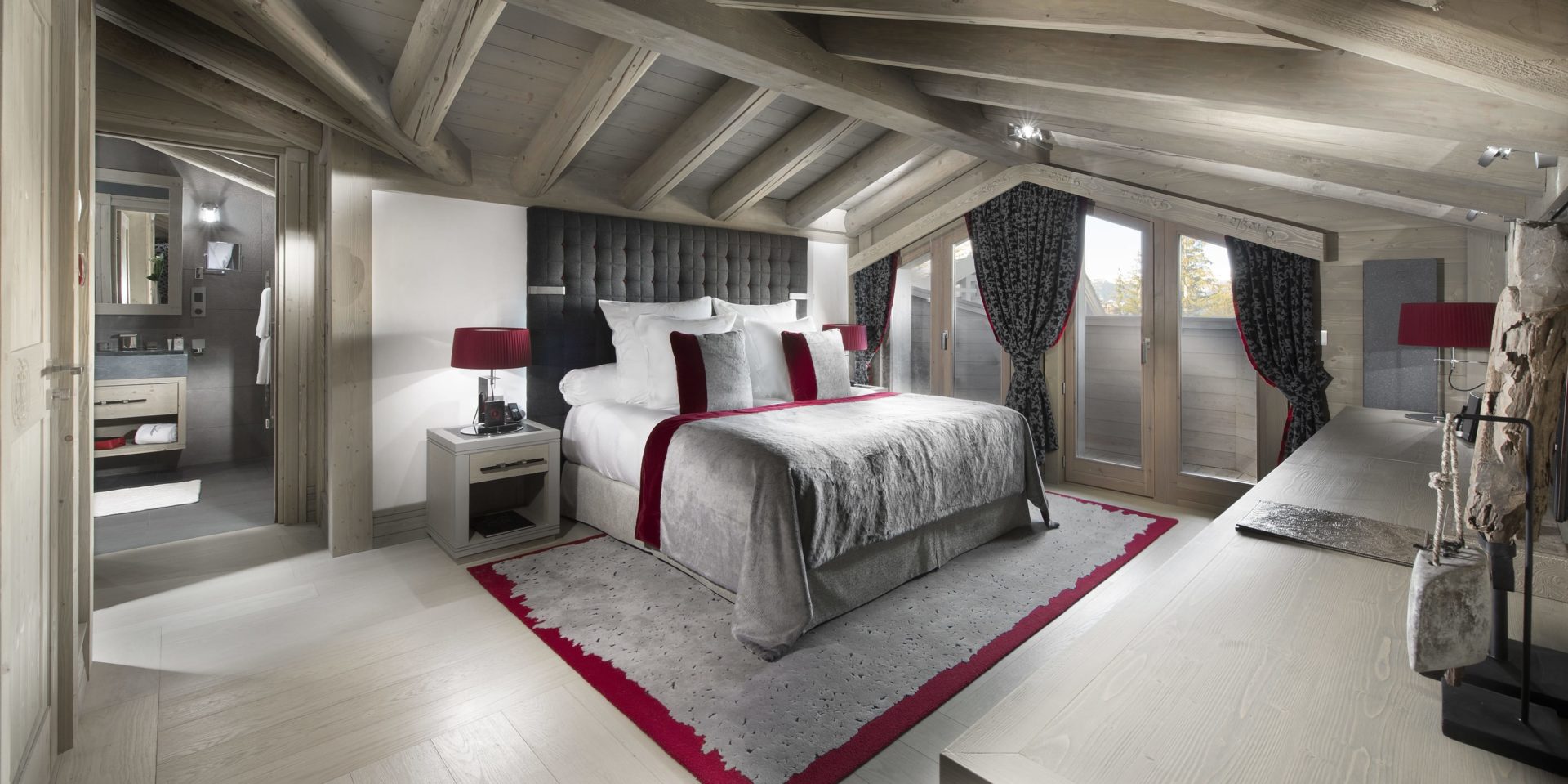 Le K2 Palace Suite-Chalet Panmah Courchevel Les 3 Vallees Frankrijk wintersport skivakantie luxe slaapkamer 2-persoonsbed hoofdbord rode kussens rode lampen vloerkleed badkamer spiegel wastafel hoge ramen houten balken