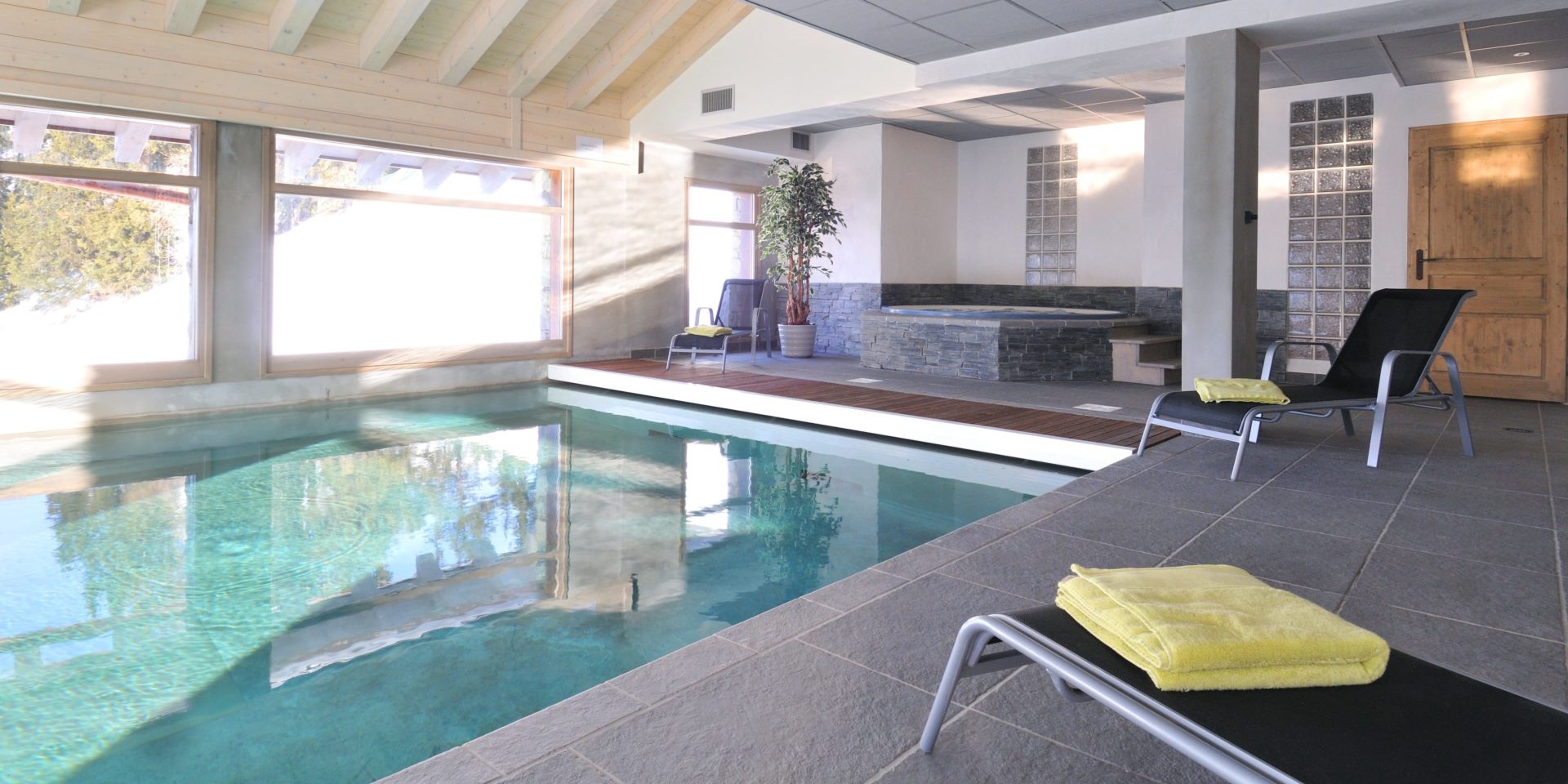 Hotel Carlina Belle Plagne Paradiski Frankrijk wintersport skivakantie luxe zwembad jacuzzi ligstoelen gele handdoeken plant grote ramen houten balken zwemmen ontspannen relaxen genieten
