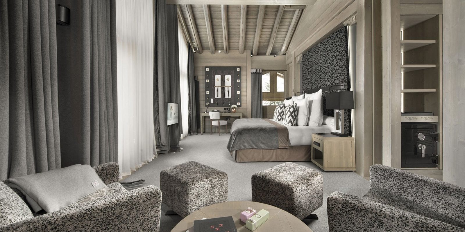 Hotel Le K2 Altitude Courchevel Les 3 Vallees Frankrijk wintersport skivakantie luxe Suite Altitude 2-persoonsbed wit bruine fauteuils hockers salontafel bureau stoel ramen houten balken