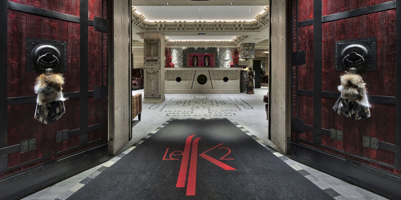 Hotel Le K2 Altitude Courchevel Les 3 Vallees Frankrijk wintersport skivakantie luxe entree Le K2 grote deuren receptie welkom hout lounge fauteuils beelden