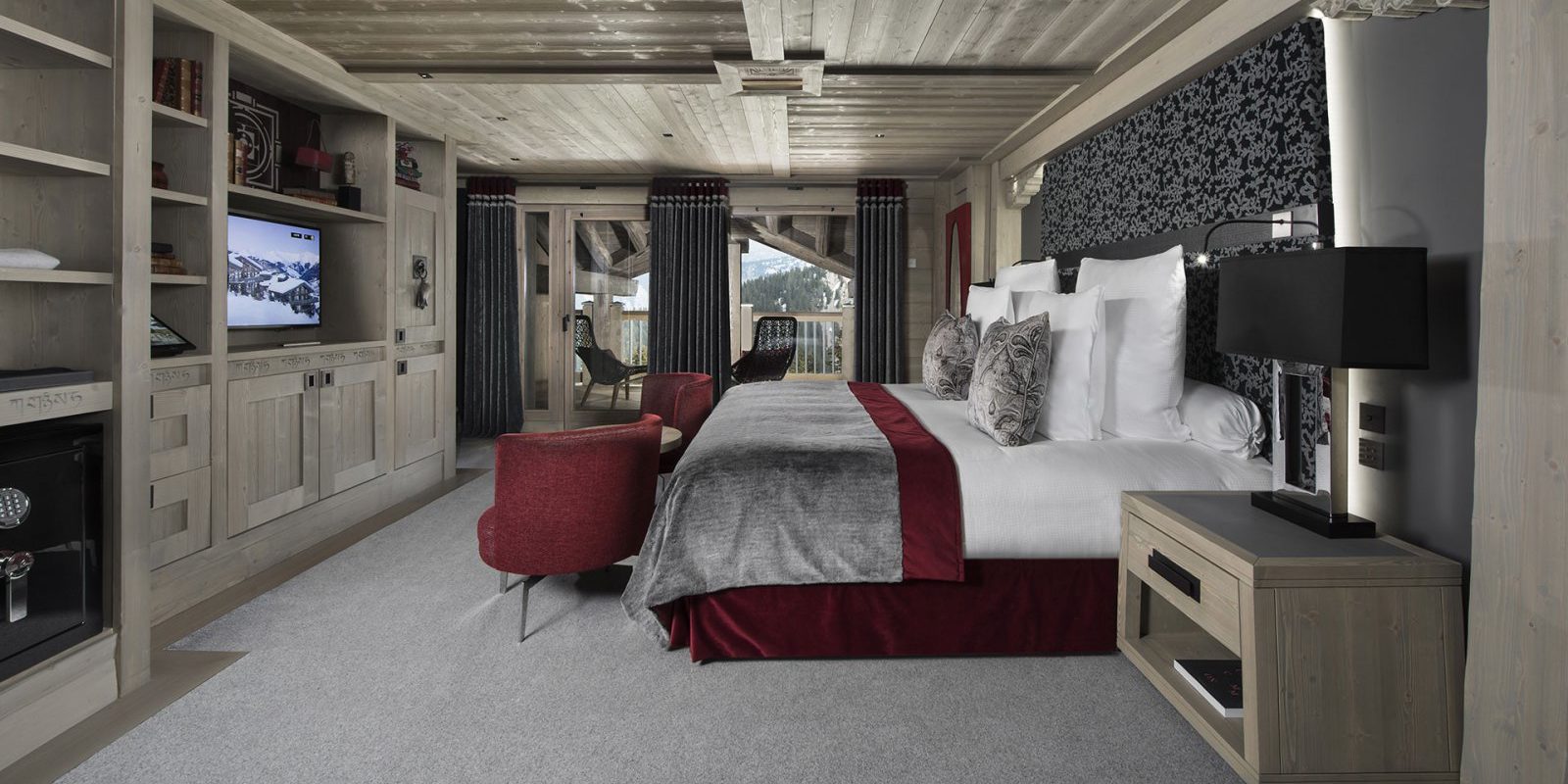 Hotel Le K2 Altitude Courchevel Les 3 Vallees Frankrijk wintersport skivakantie luxe slaapkamer 2-persoonsbed rode fauteuils TV houten wandksat zwart wit behand houten plafond balkon stoelen
