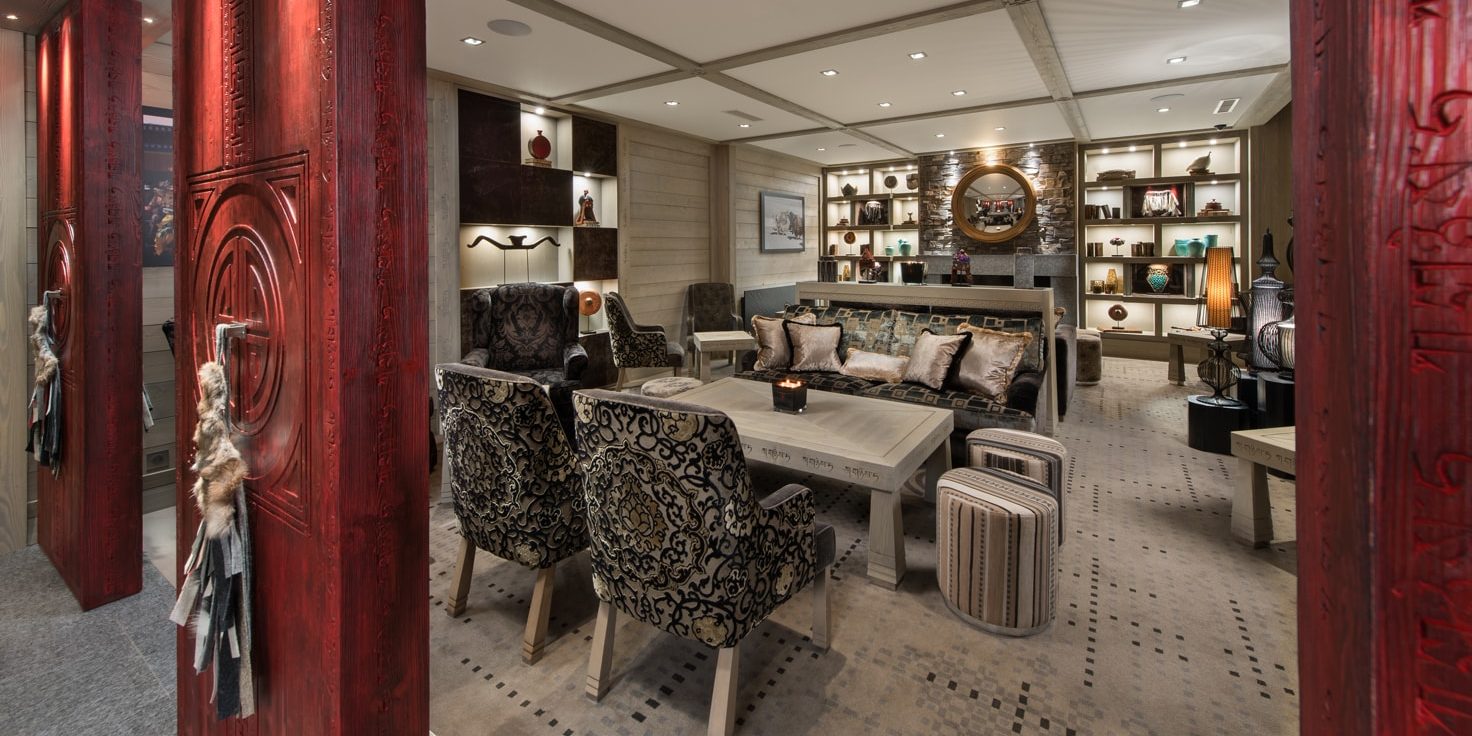 Hotel Le K2 Djola Courchevel Les 3 Vallees Frankrijk wintersport skivakantie luxe lounge bank kussens fauteuils salontafel hockers spiegel rode pilaren vazen vloerbedekking