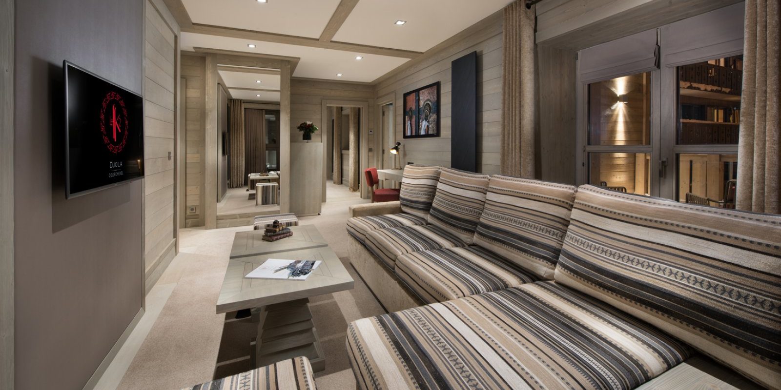 Hotel Le K2 Djola Courchevel Les 3 Vallees Frankrijk wintersport skivakantie luxe TV kamer gestreepte loungebank chaise longue salontafels raam hout bureau stoel spiegel
