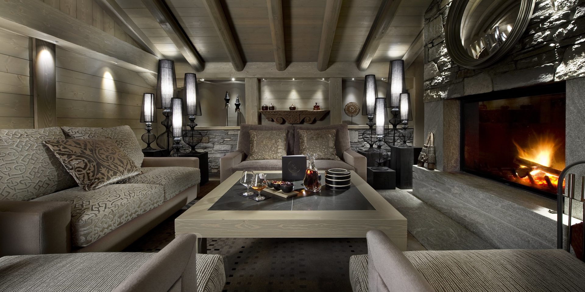 Hotel Le K2 Palace Courchevel Les 3 Vallees Frankrijk wintersport skivakantie luxe Bar 8611 lounge bank fauteuils salontafel Cognac glazen open haard ronde spiegel houten balken houten plafond lampen