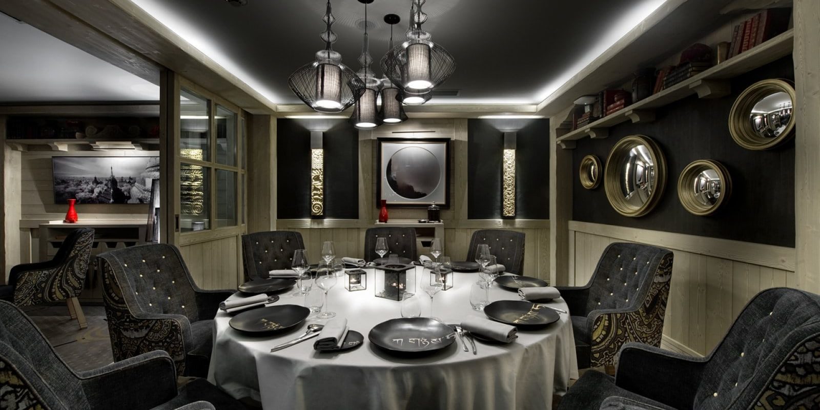Hotel Le K2 Palace Courchevel Les 3 Vallees Frankrijk wintersport skivakantie luxe restaurant Black Pyramid gedekte tafel wijnglazen stoelen hangende lampen ronde spiegels houten lambrisering boeken
