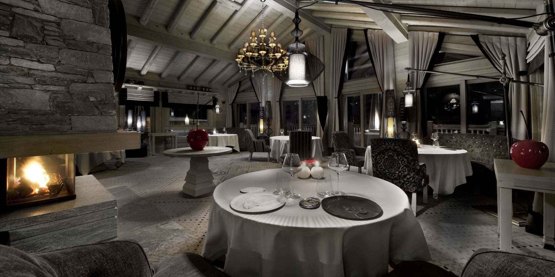 Hotel Le K2 Palace Courchevel Les 3 Vallees Frankrijk wintersport skivakantie luxe Le Kintessence restaurant gedekte tafels stoelen open haard kroonluchter hoge ramen houten balken houtne plafond rode appels