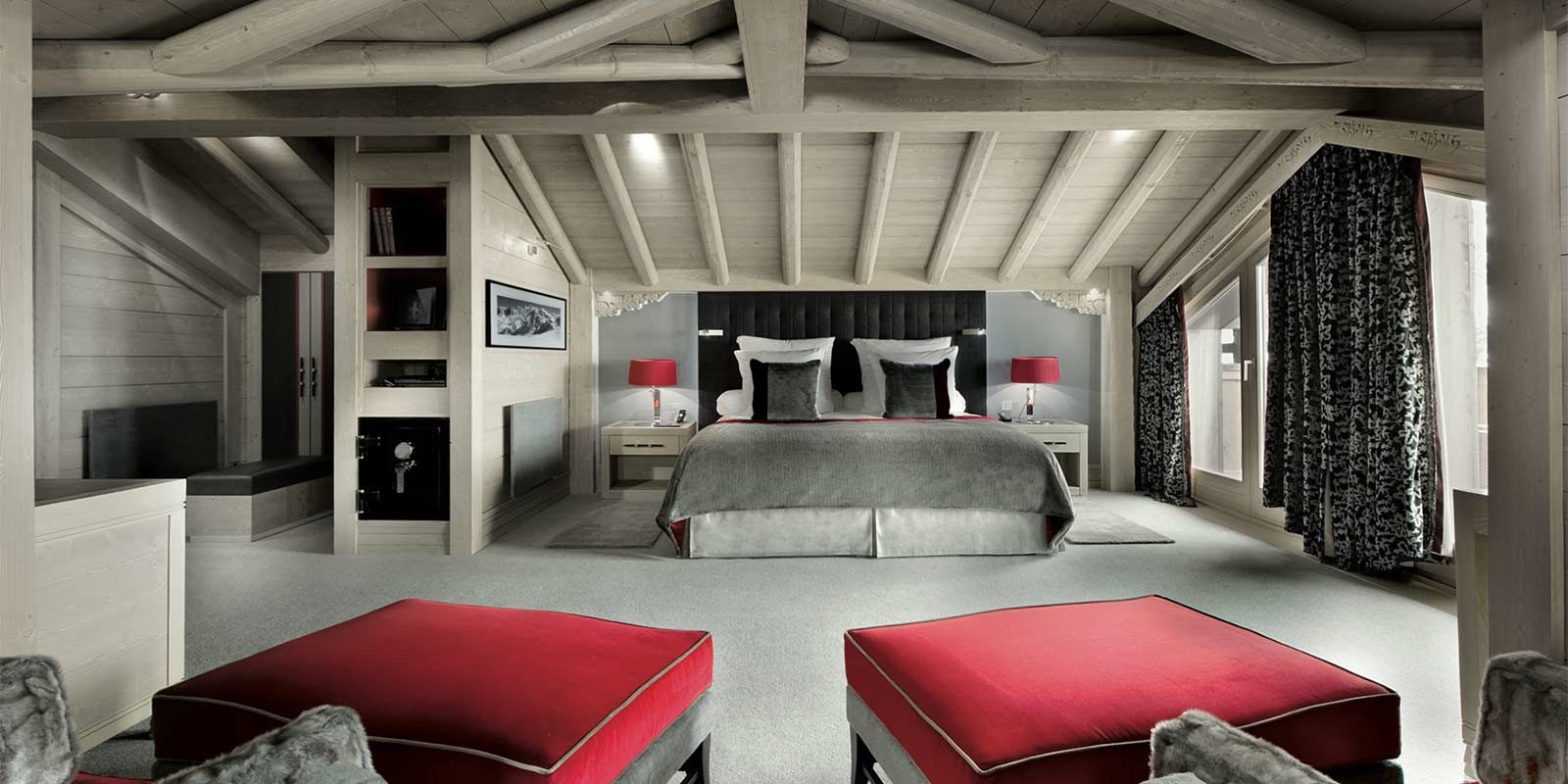 Hotel Le K2 Palace Courchevel Les 3 Vallees Frankrijk wintersport skivakantie luxe Suite 2-persoonsbed fauteuils rode hockers vloerbedekking hoge ramen houten balken houten plafond