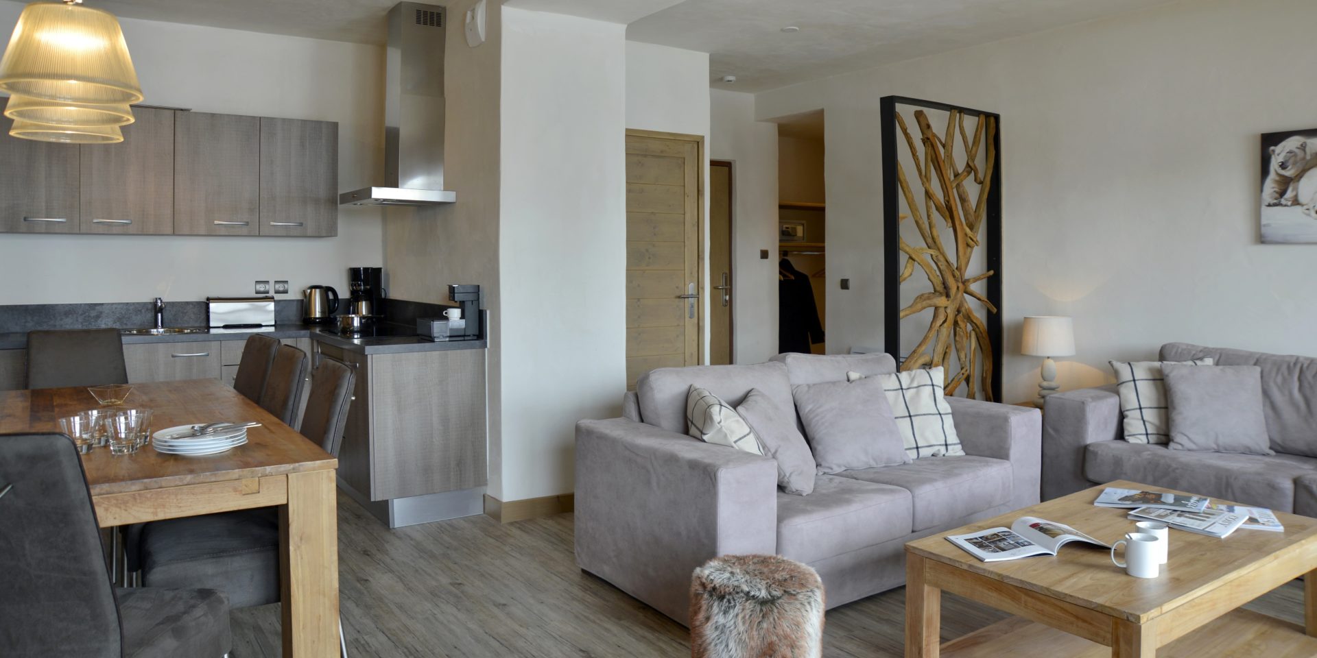 Residence Carlina Belle Plagne Paradiski Frankrijk wintersport skivakantie luxe living eettafel handlampen stoelen grijze banken kussens salontafel hocker schilderij ijsbeer keuken kamerscherm