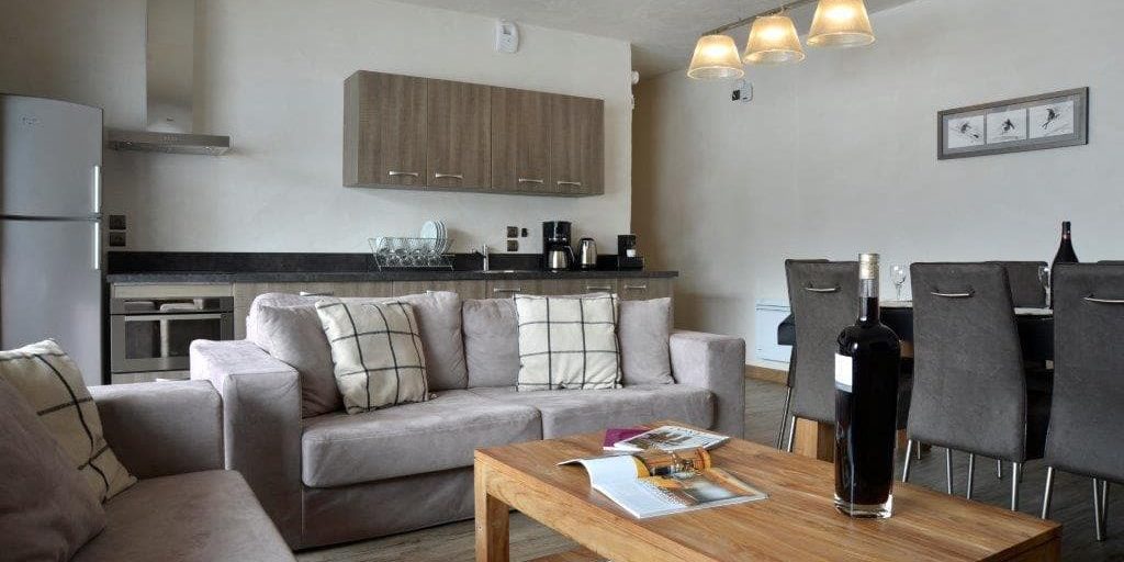 Residence Carlina Belle Plagne Paradiski Frankrijk wintersport skivakantie luxe living eettafel handlampen stoelen grijze banken kussens salontafel likeur schilderij keuken