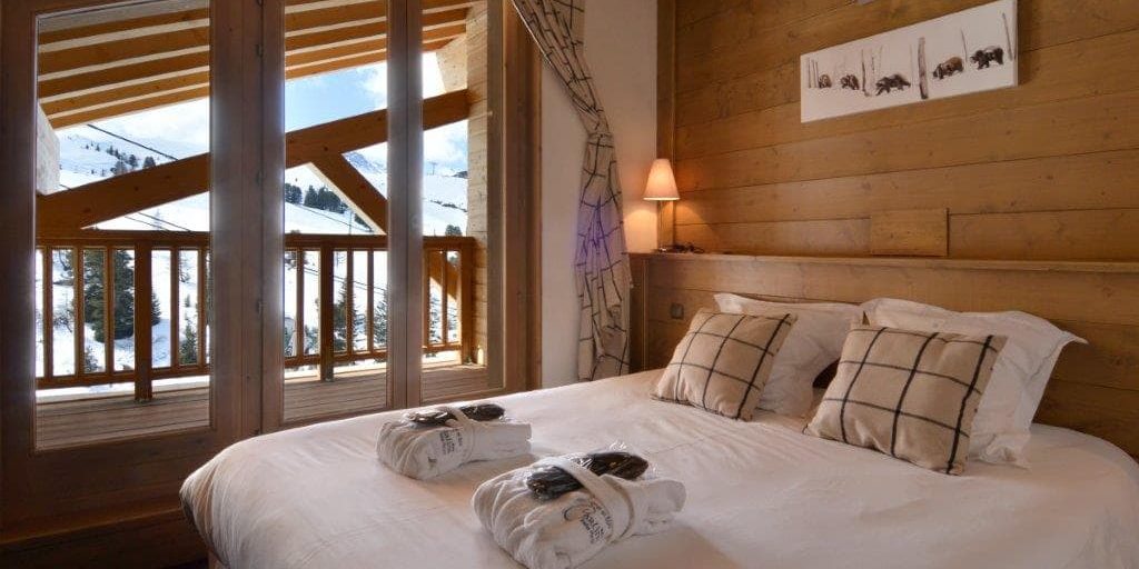 Residence Carlina Belle Plagne Paradiski Frankrijk wintersport skivakantie luxe slaapkamer 2-persoonsbed badjassen schilderijen ijsberen raam balkon houten wand bomen sneeuw