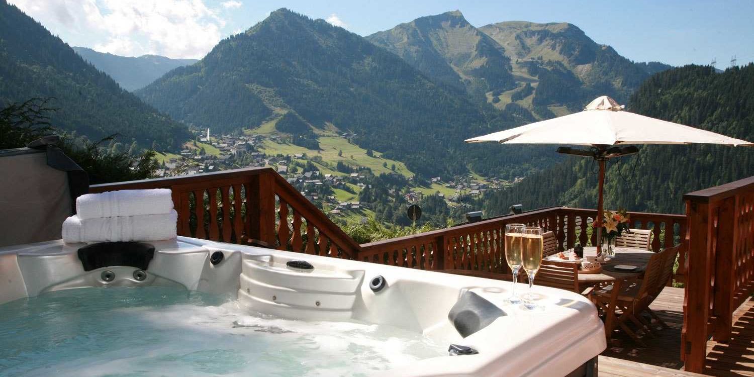 Chalet Belle Vache Chatel Les Portes du Soleil Frankrijk wintersport skivakantie luxe hot tub Champagne balkon tafel stoelen parasol uitzicht bomen dorp Chatel bergen