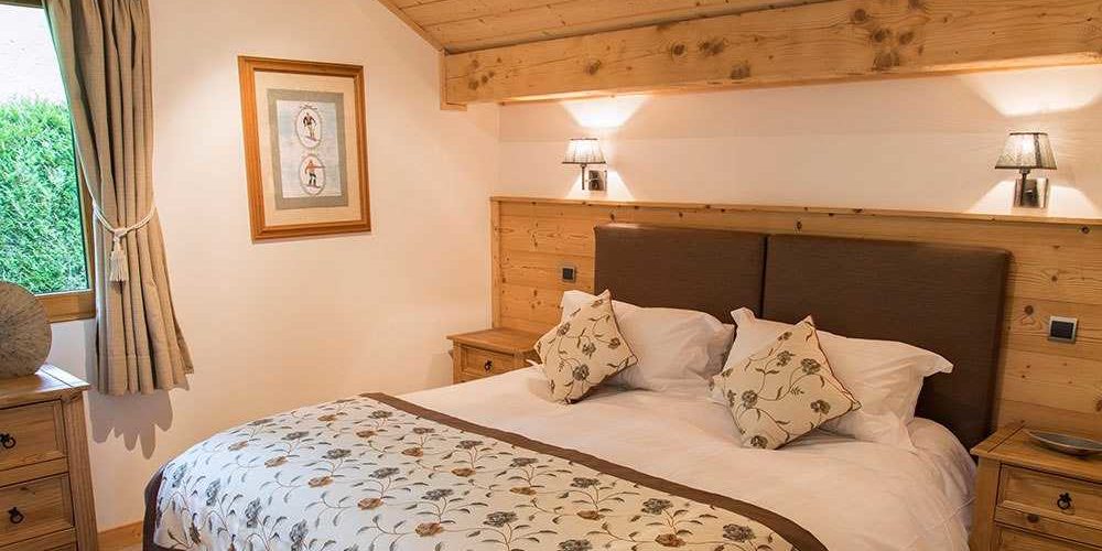 Chalet Belle Vache Chatel Les Portes du Soleil Frankrijk wintersport skivakantie luxe slaapkamer 2-persoonsbed schilderij wandlampen houten plafond balkon raam bomen