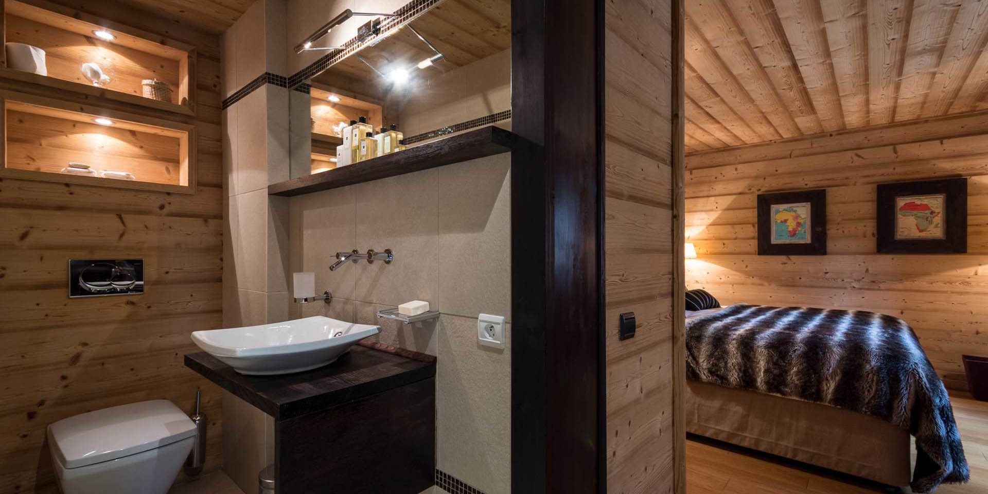 Chalet Ferme de Moudon Les Gets Les Portes du Soleil Frankrijk wintersport skivakantie luxe badkamer wastafel spiegel slaapkamer 2-persoonsbed sprei schilderijen houten wanden houten plafond