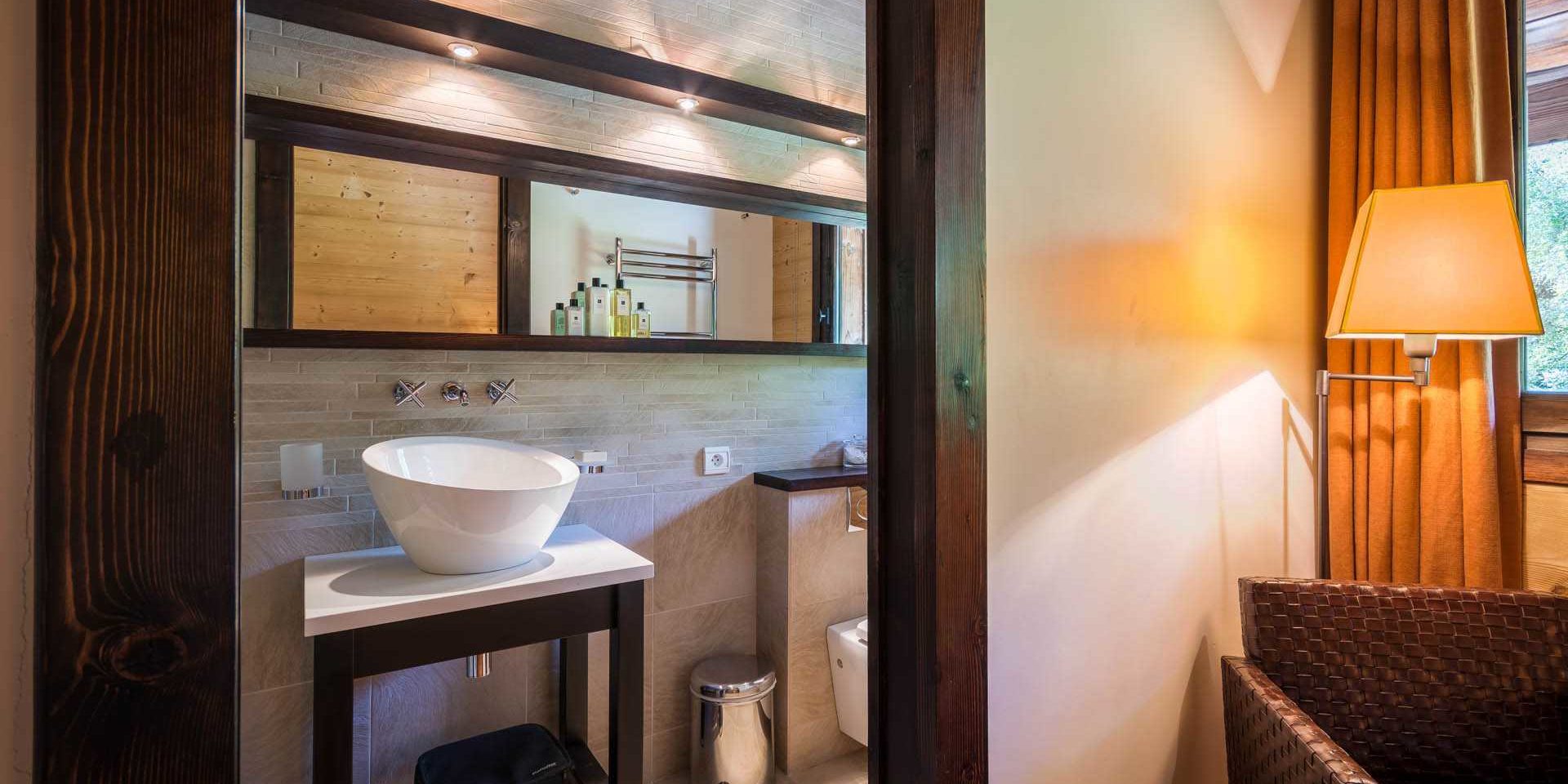 Chalet Ferme de Moudon Les Gets Les Portes du Soleil Frankrijk wintersport skivakantie luxe badkamer wastafel grote spiegel spotjes badproducten fauteuil lamp raam