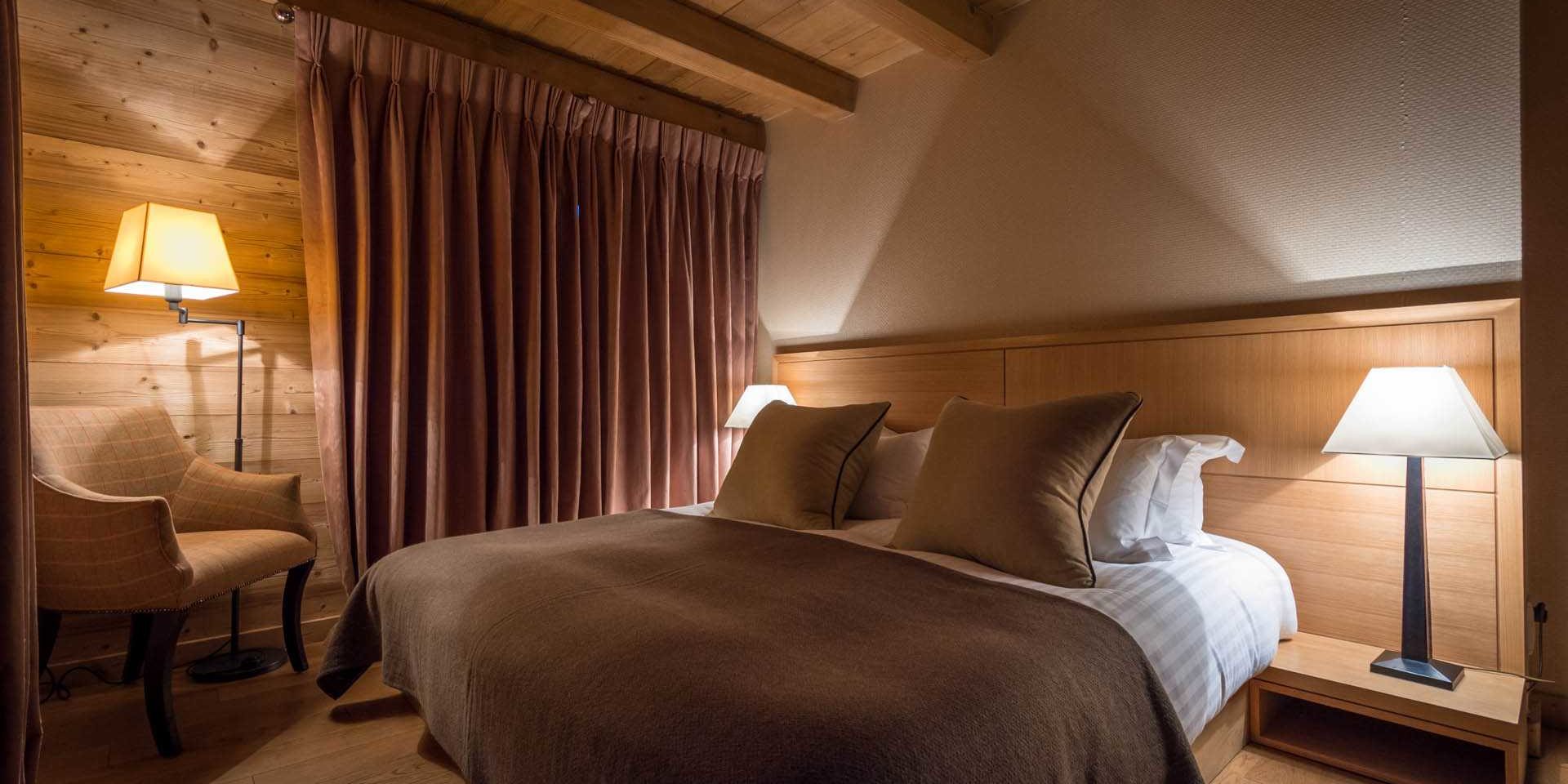 Chalet Ferme de Moudon Les Gets Les Portes du Soleil Frankrijk wintersport skivakantie luxe slaapkamer 2-persoonsbed sprei nachtlampjes fauteuil gordijnen houten balken