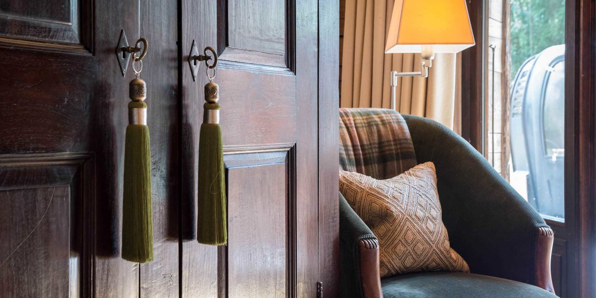 Chalet Ferme de Moudon Les Gets Les Portes du Soleil Frankrijk wintersport skivakantie luxe fauteuil kussen geblokt kleed kast lamp raam deur