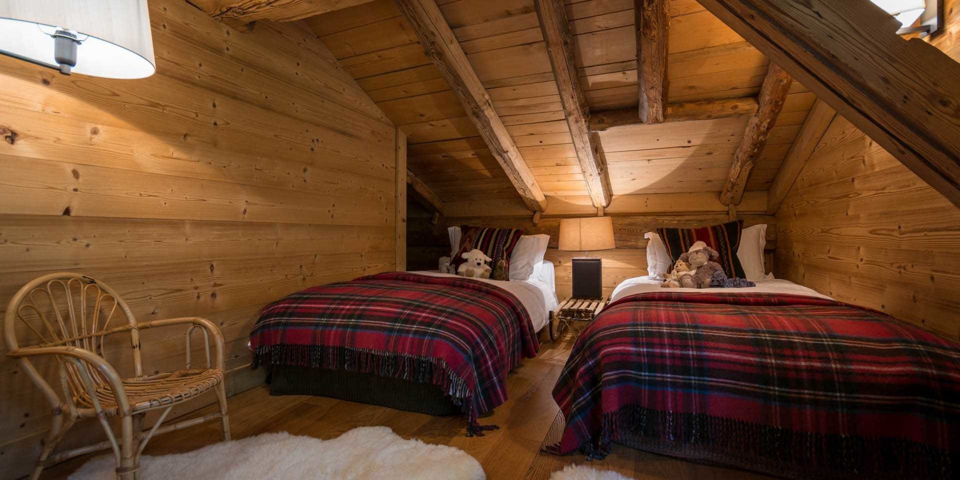 Chalet Ferme de Moudon Les Gets Les Portes du Soleil Frankrijk wintersport skivakantie luxe slaapkamer aparte bedden geblokte sprei knuffels stoel kinderkamer houten wanden houten balken vloerkleed nachtlampje