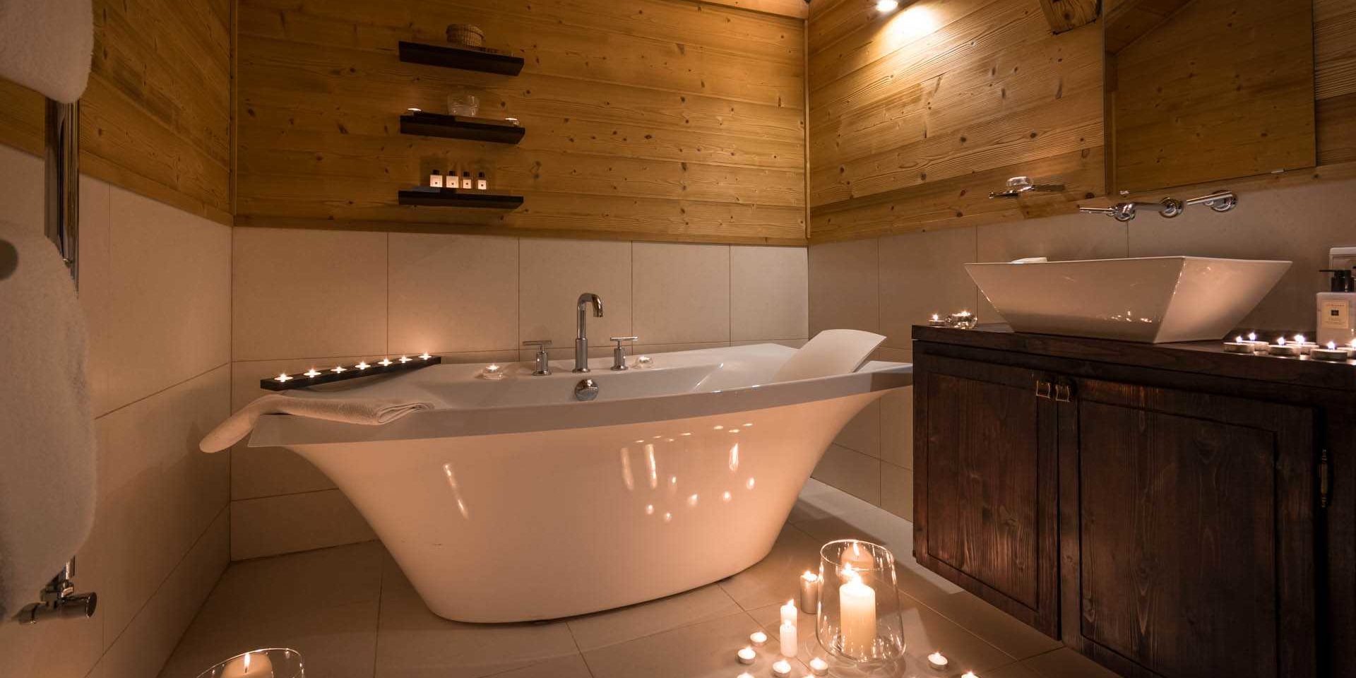 Chalet Ferme de Moudon Les Gets Les Portes du Soleil Frankrijk wintersport skivakantie luxe badkamer vrijstaand wit bad kaarsen wastafel spiegel handdoekenrek houten muur
