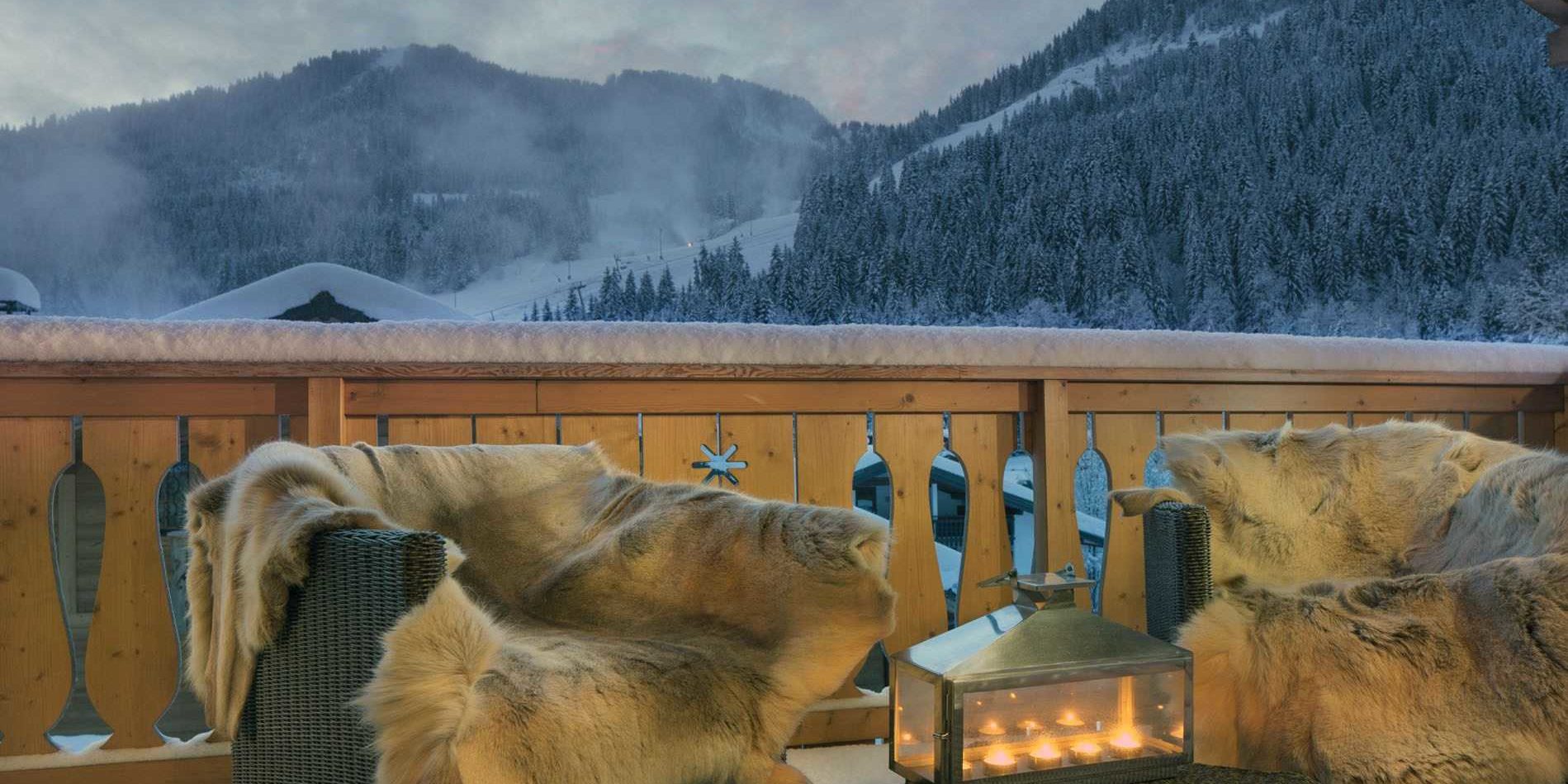 Chalet Grand Coeur Chatel Les Portes du Soleil Frankrijk wintersport skivakantie luxe balkon fauteuils kleden windlicht uitzicht besneeuwde bomen besneeuwde bergen besneeuwde daken sneeuw