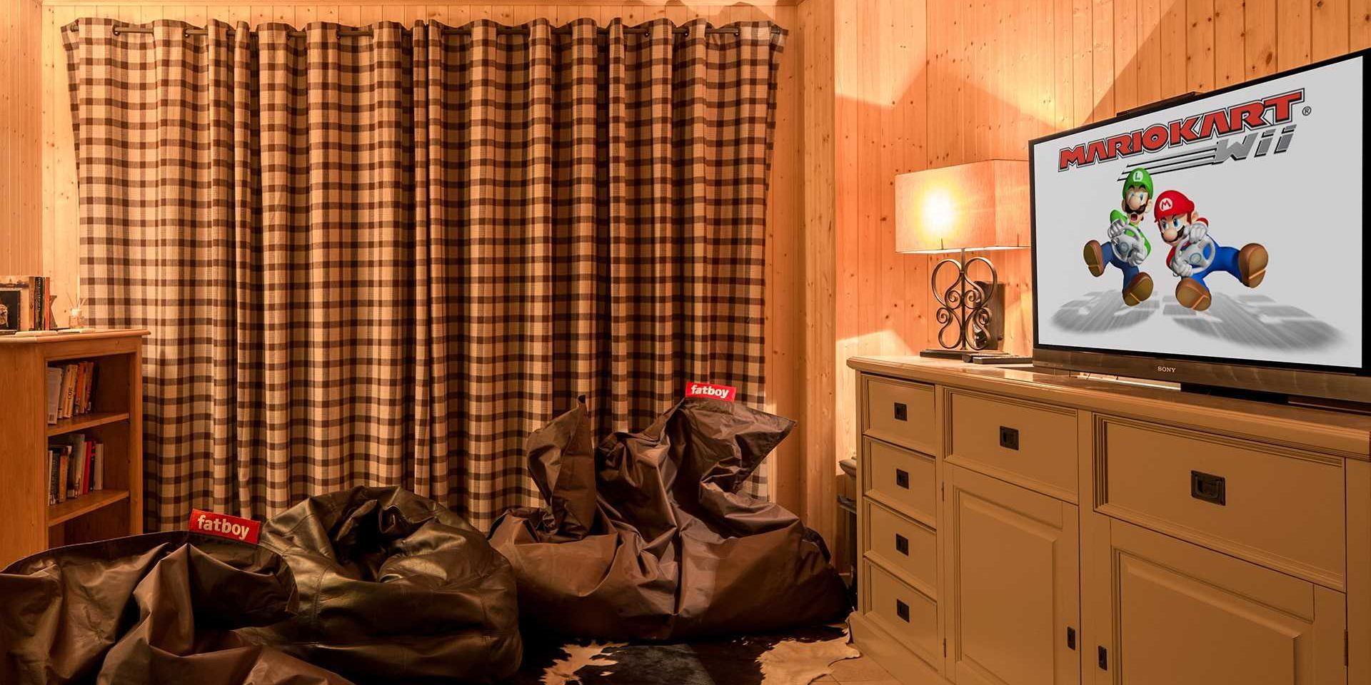 Chalet Grand Coeur Chatel Les Portes du Soleil Frankrijk wintersport skivakantie luxe game room zitzakken flatscreen TV vloerkleed geblokte gordijnen houten wanden kast boeken Mario kart