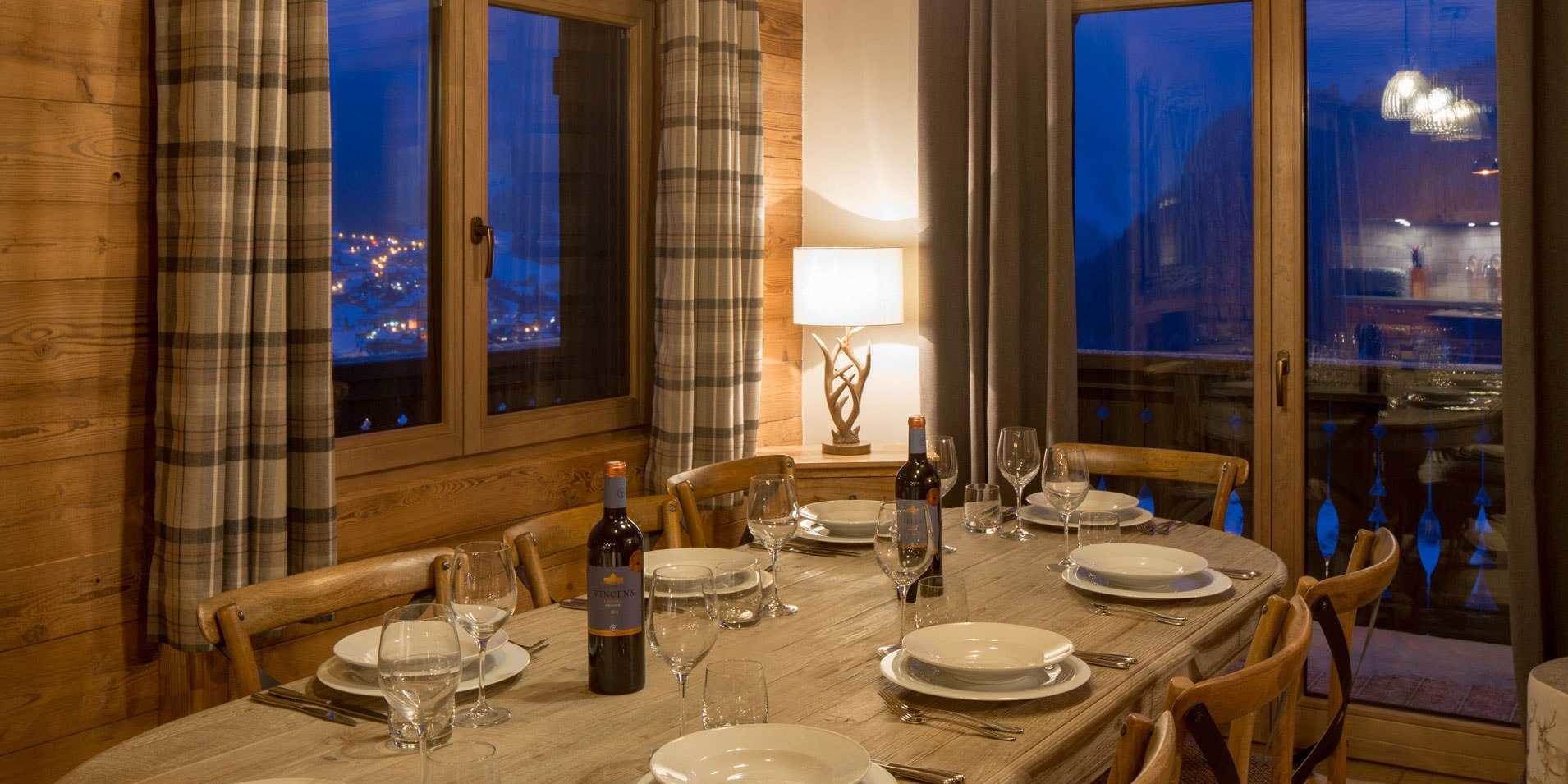 Chalet Les Clarines Chatel Les Portes du Soleil Frankrijk wintersport skivakantie luxe eetkamer gedekte tafel wijn wijnglazen houten stoelen lamp raam balkon bomen bergen sneeuw